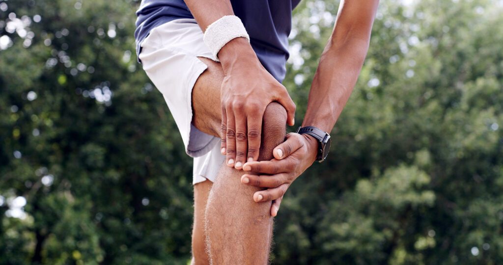 An athlete holding their knee and raising it to avoid pain.